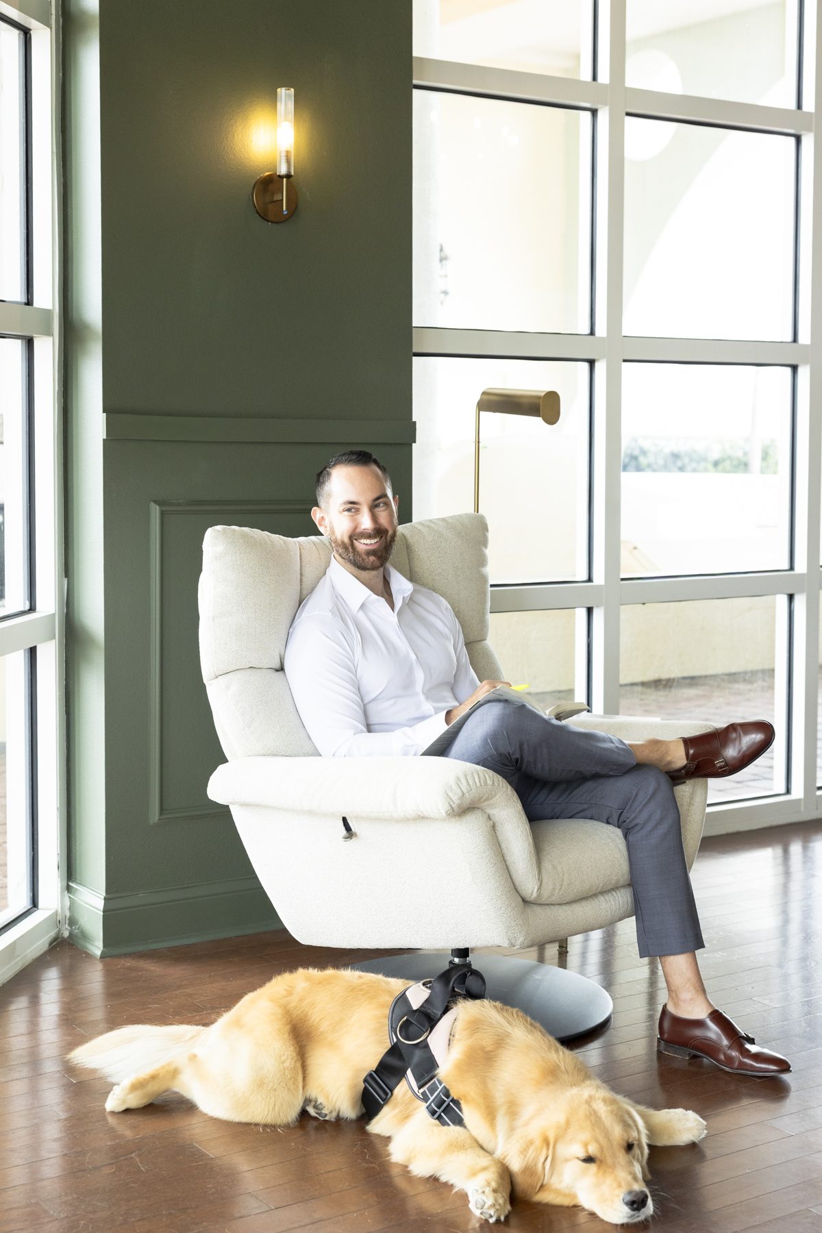 Jesse Plunkett in an armchair by the office windows with his golden retriever, Nala