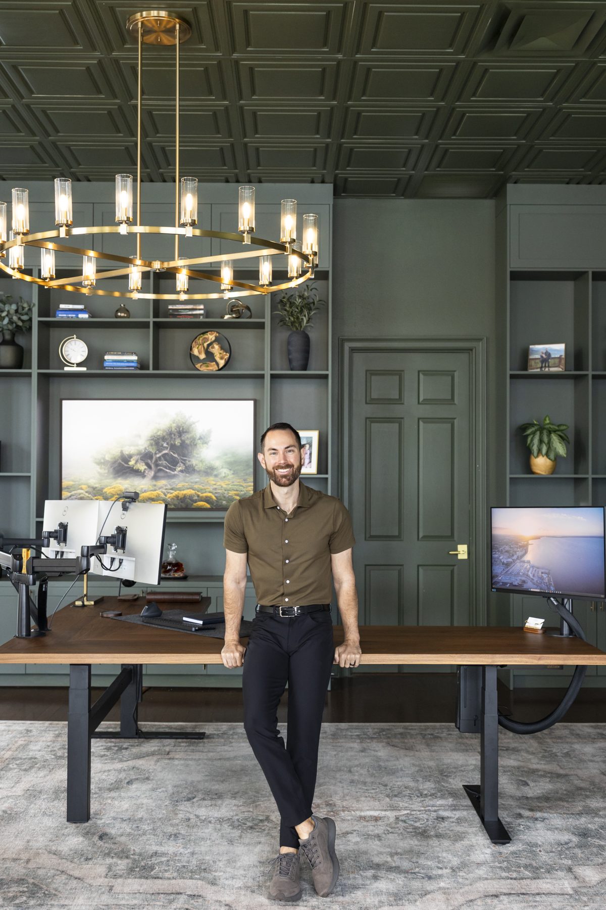 Jesse Plunkett standing at his desk in the True Stewards office, chandelier overhead