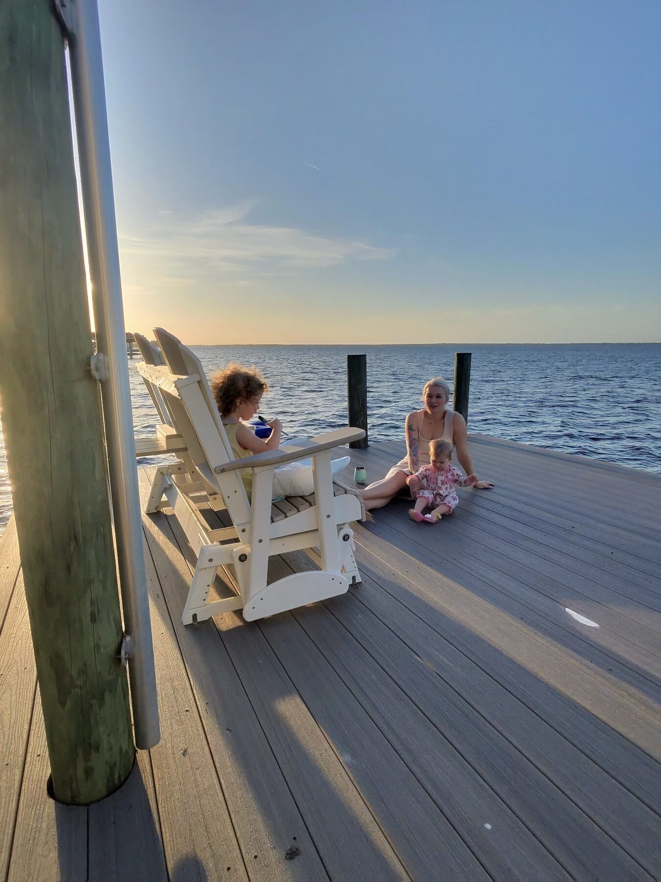 Jesse's daughters standing on a wooden dock by the water at golden hour