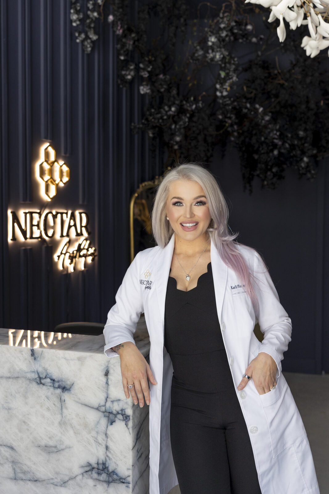 Karli, a medical spa founder and injector, in her lab coat at the front desk of her practice